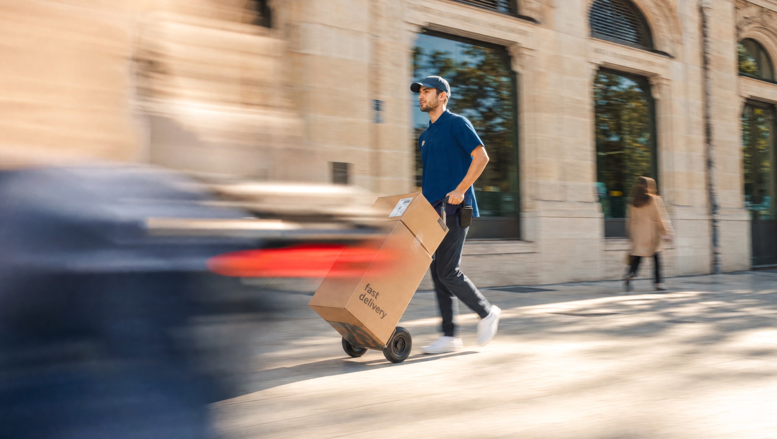 Courier wheeling parcels down a city street on a hand truck